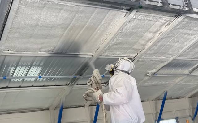 Closed cell foam being applied to the underside of a high open roof deck